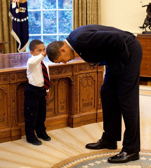 President Obama bends to 5-year-old Jacob Philadelphia, whose arm raised to touch the president’s hair — to see if it feels like his.