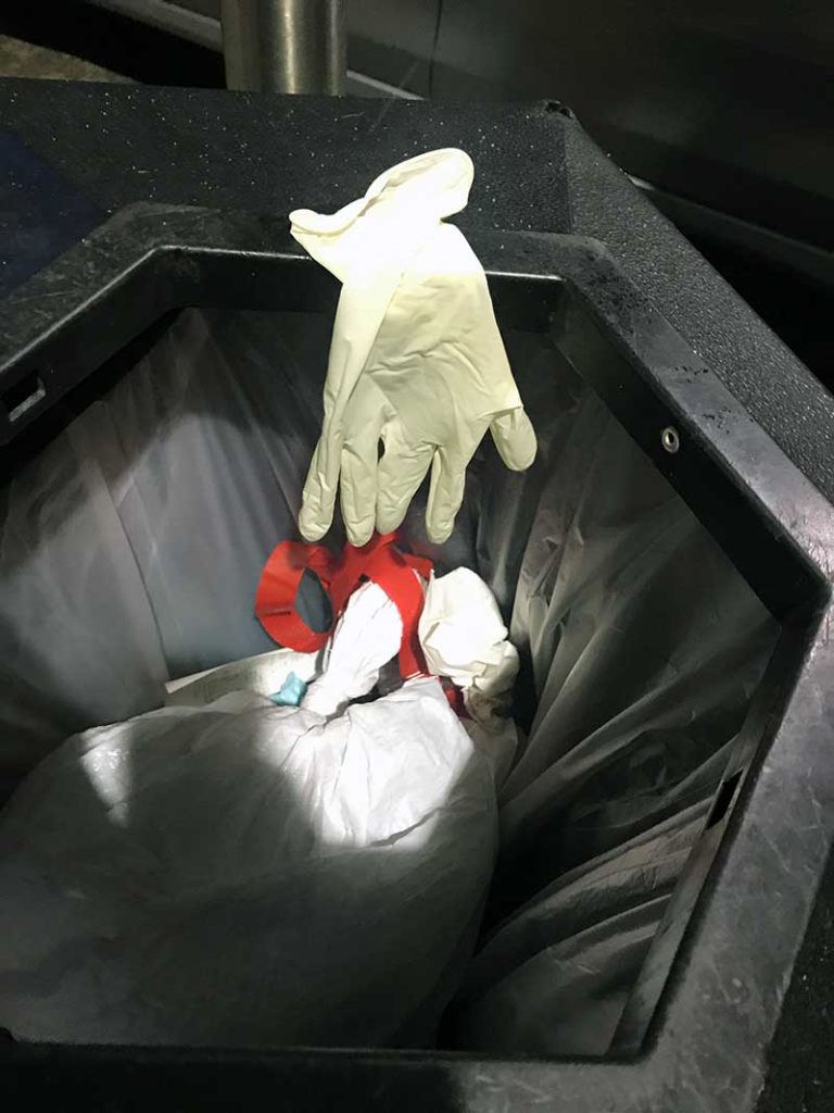 Close up rubber glove draped over trash can. 
