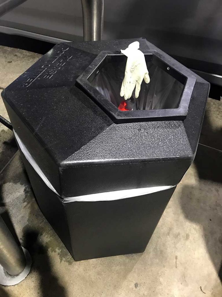 Rubber glove draped over trash can.